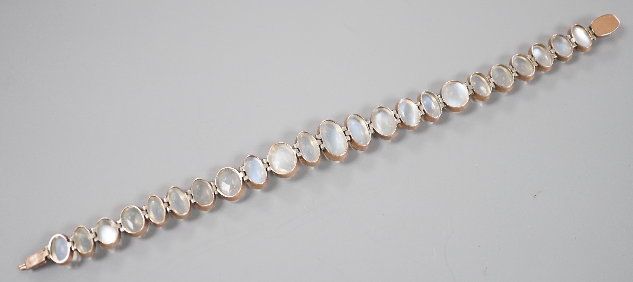 An Edwardian white and yellow metal, graduating oval cabochon moonstone set bracelet, 18cm, gross weight 14.6 grams.